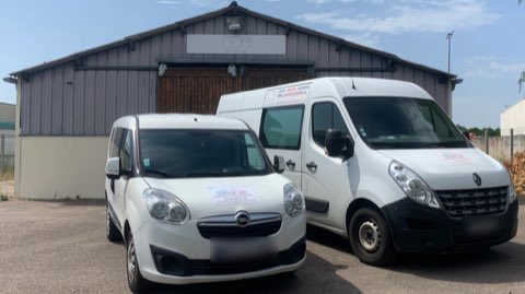Deux utilitaires blancs aux couleurs d’Afficom garés devant le bâtiment de l’entreprise.