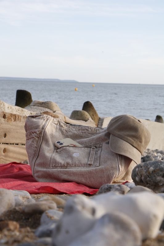 Sac en toile posé sur une serviette rouge, sur la plage.