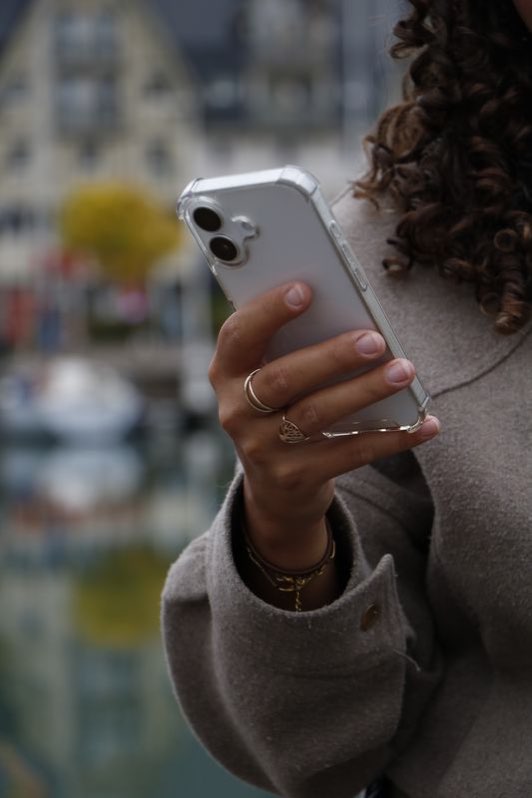 Main tenant un smartphone, sur fond de port flou.